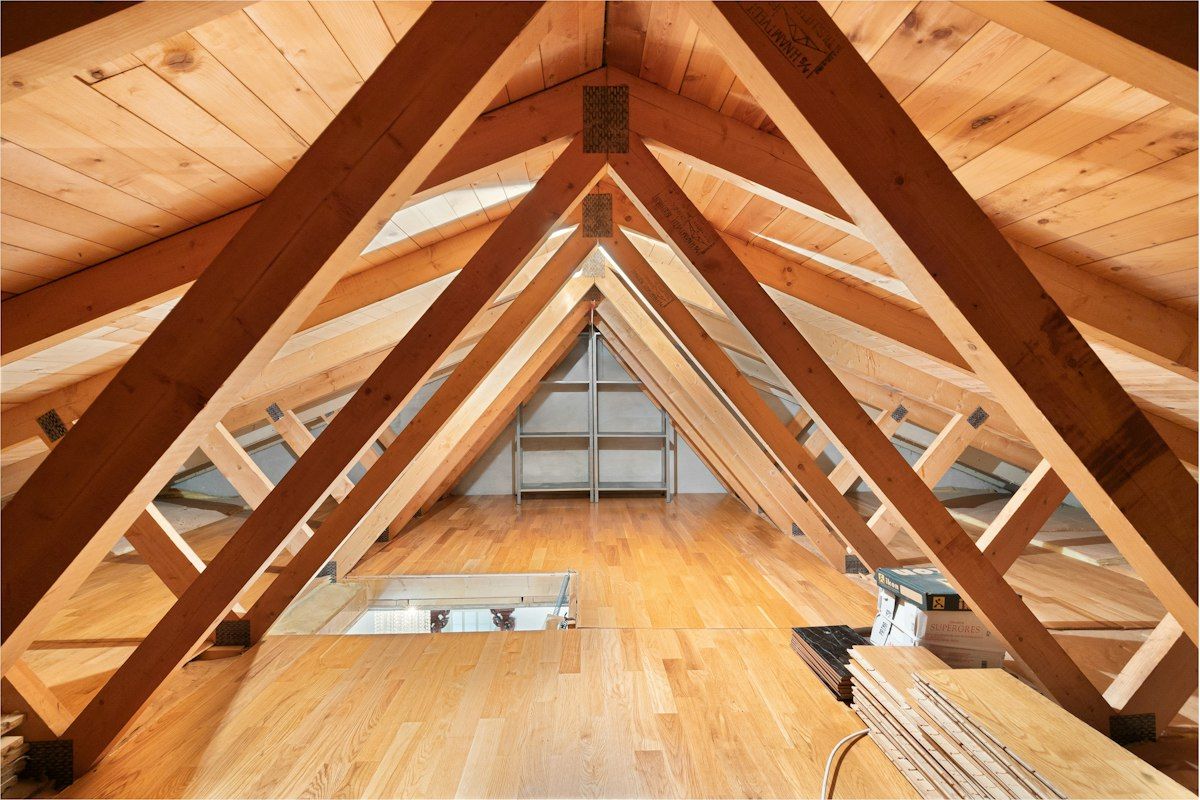 Attic with dark water stains on the roof decking and damp insulation, interior signs of roof damage